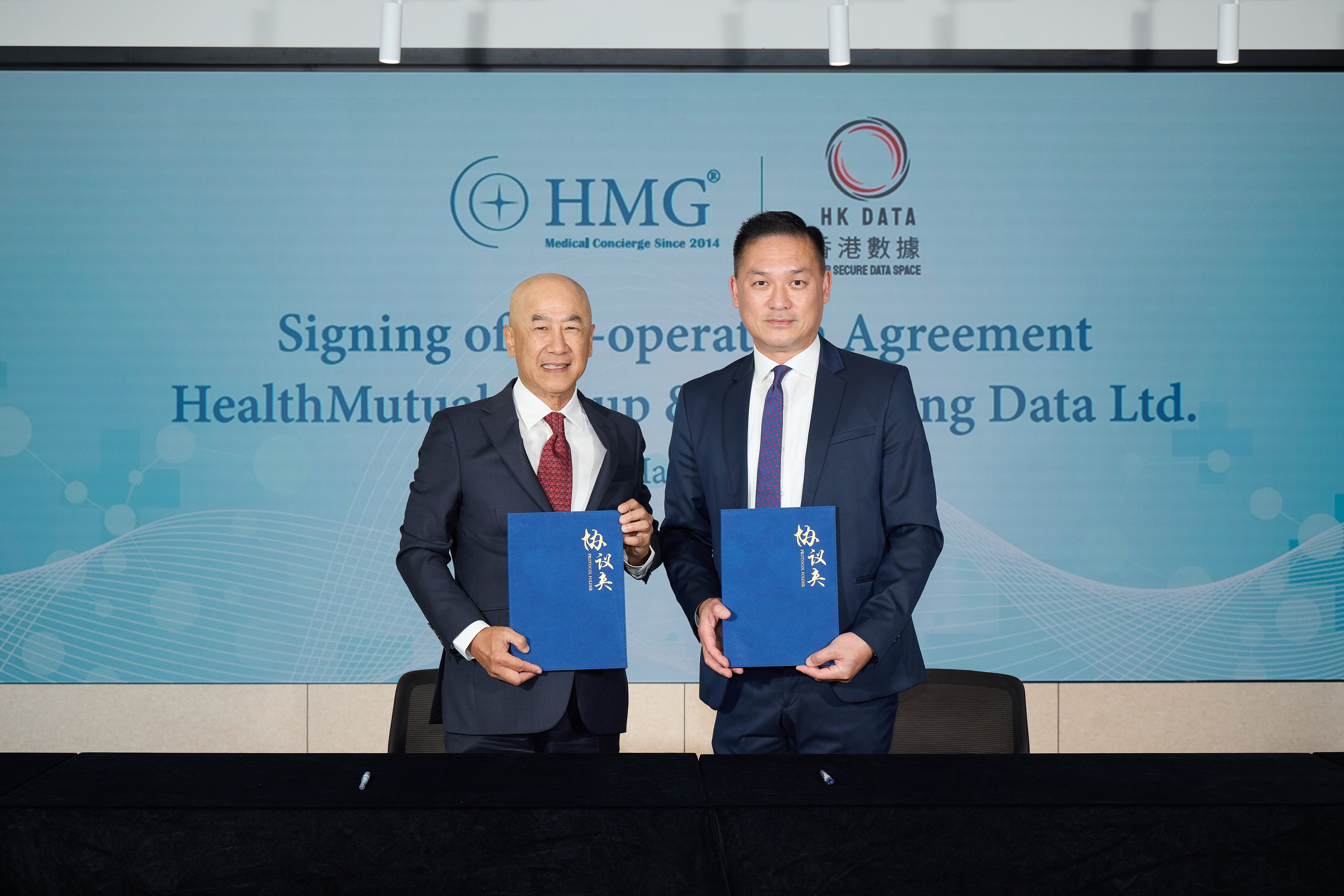 Mr. KC Chan and Mr. Aldous Ng seated signing